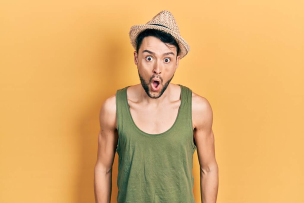Fiatal spanyol férfi visel nyári kalap fél, és megdöbbent a meglepetés kifejezés, félelem és izgatott arc.  - Fotó, kép