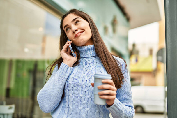 Młoda latynoska dziewczyna rozmawia przez smartfona i pije kawę w mieście - Zdjęcie, obraz