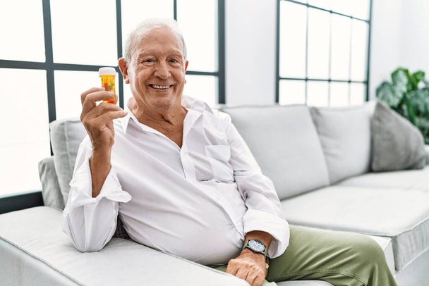 Старший чоловік тримає таблетки з щасливою і холодною посмішкою на обличчі. щаслива людина
.  - Фото, зображення