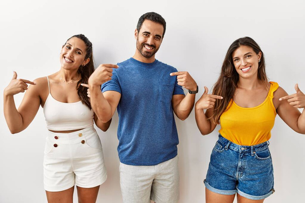Група молодих іспаномовних людей, що стоять над ізольованим тлом, впевнено виглядає з посмішкою на обличчі, вказуючи на себе з гордими і щасливими пальцями
.  - Фото, зображення