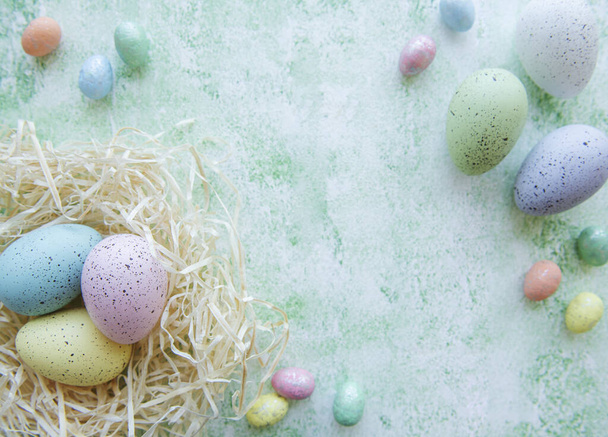 Velikonoční vajíčka v slámovém hnízdě na zeleném dřevěném pozadí - Fotografie, Obrázek