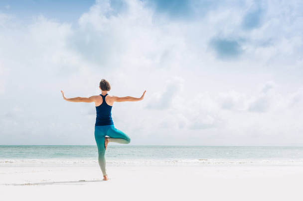 Caucasian woman practicing yoga at seashore - Foto, imagen