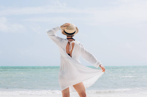 Happy traveller woman in white dress and hat enjoys her tropical beach vacation - Φωτογραφία, εικόνα