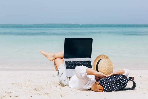 Mujer joven trabajando, usando un ordenador portátil en una playa. Trabajo independiente, vacaciones, trabajo a distancia, distanciamiento social, e-learning, conexión, profesional creativo, nuevo negocio, reunión de concepto en línea - Foto, imagen