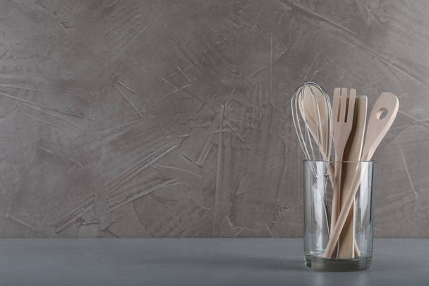 Holder with wooden kitchen utensils on grey table. Space for text - Фото, изображение