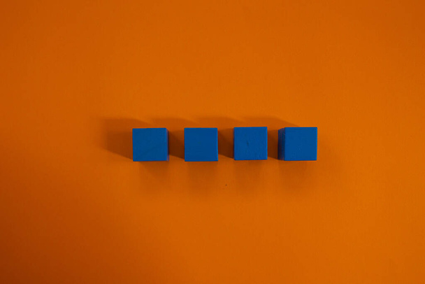 Four wooden cubes isolated on orange background. Top view blank wooden cubes. - Fotó, kép
