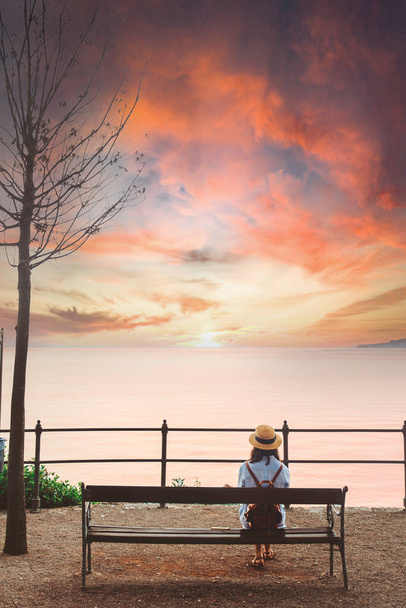 Frau sitzt auf Bank und blickt aufs Meer - Foto, Bild