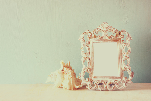 Low key image of vintage antique classical frame and seashell on wooden table. filtered image - Foto, Imagem