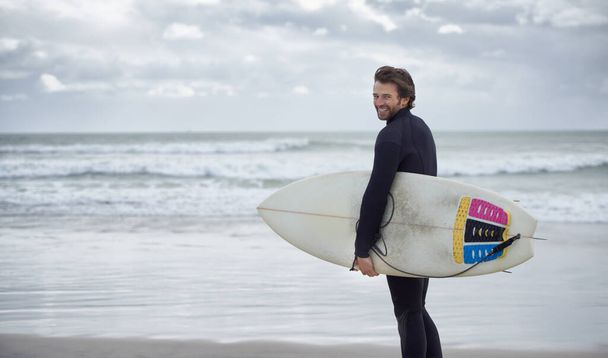 Na plażę. Surfer z deską surfingową na plaży. - Zdjęcie, obraz