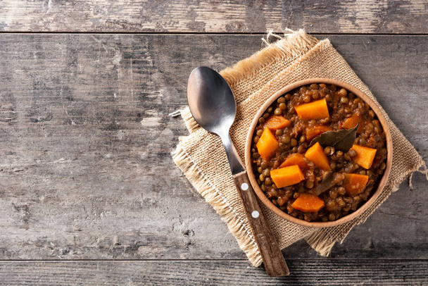 Lentil stew ragout with pumpkin and carrot in bowl on wooden table. Top view. Copy space - Photo, Image