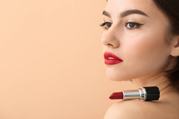 Beautiful woman with red lips and lipstick on shoulder against color background - Photo, Image
