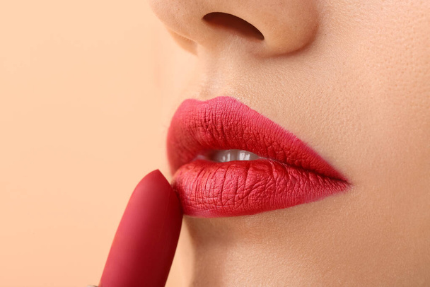 Attractive young woman applying red lipstick, closeup - Photo, Image