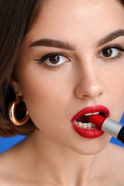 Beautiful woman with red lips biting lipstick, closeup - Photo, Image