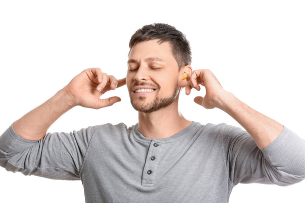 Bonito homem colocando tampões de ouvido amarelo no fundo branco - Foto, Imagem