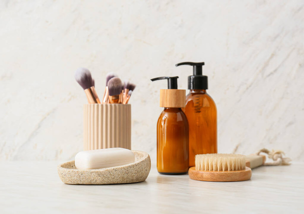 Bowl with soap bar, cosmetics and massage brush on light background - Photo, Image