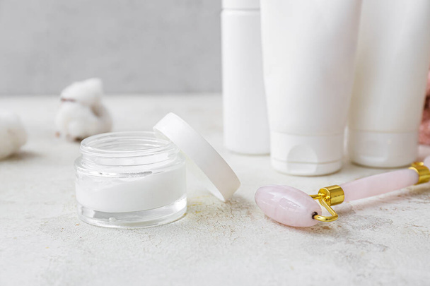 Jar of cosmetic product and facial massage tool on light background, closeup - Photo, Image
