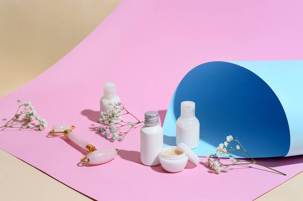 Різні косметичні продукти, інструмент для масажу обличчя та квіти гіпсофіли на кольоровому фоні
 - Фото, зображення