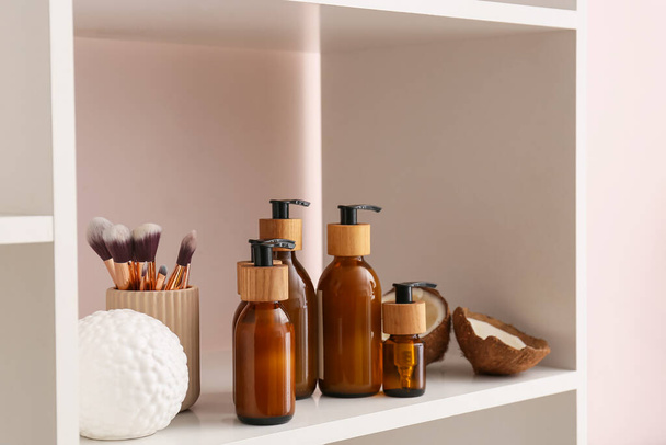 Пляшки косметичних засобів і пензлі для макіяжу на полиці, крупним планом
 - Фото, зображення