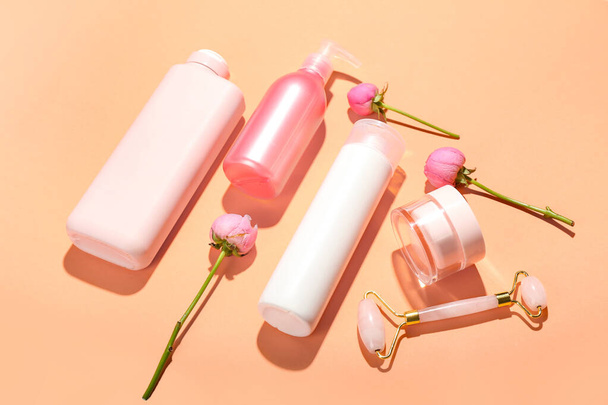 Samenstelling met cosmetische producten, gezichtsmassage tool en roos bloemen op kleur achtergrond - Foto, afbeelding