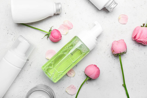 Composição com diferentes produtos cosméticos e flores de rosa em fundo claro - Foto, Imagem