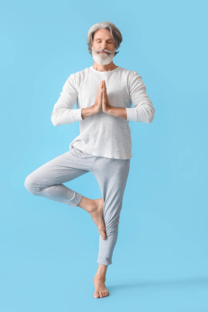 Mature man practicing yoga on color background - Fotoğraf, Görsel
