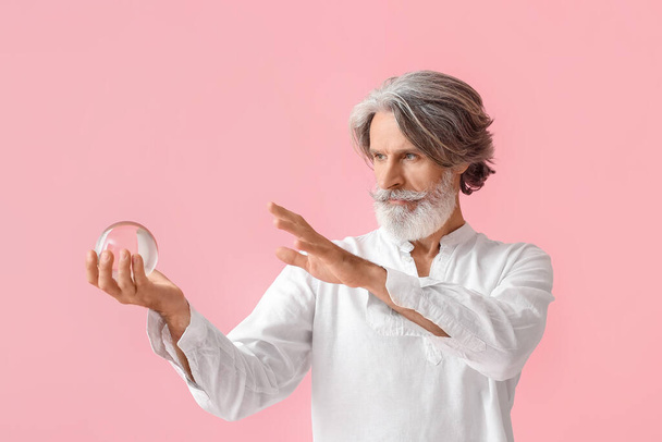 Mature man with crystal ball on color background - Fotografie, Obrázek
