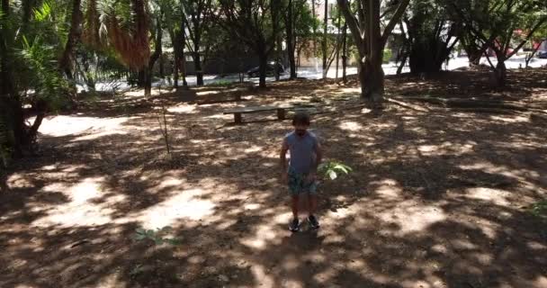 mladý muž běží ve dne se zeleným parkem v pozadí - Záběry, video