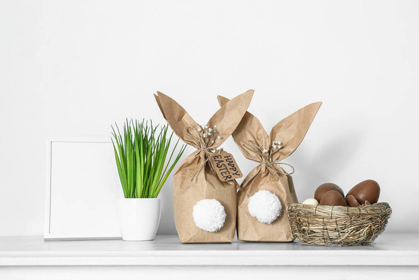 Paper bags bunny with chocolate eggs on table in room - Foto, imagen