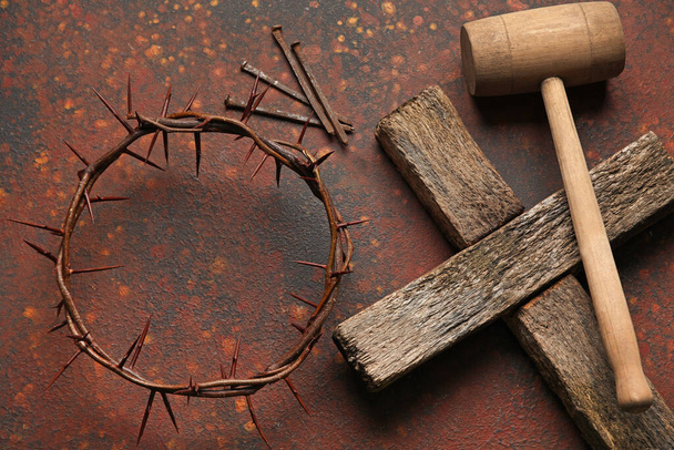 Kroon van doornen met houten kruis, hamer en spijkers op kleur achtergrond - Foto, afbeelding