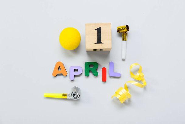 Komposition mit Datum 1 APRIL und Partydekor auf hellem Hintergrund. Feier zum Aprilscherz - Foto, Bild