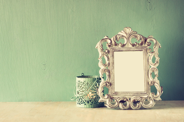 Low key image of vintage antique classical frame and white lantern on wooden table. filtered image - Foto, imagen