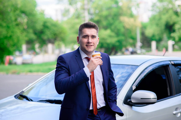 A businessman drinks coffee near his car - Фото, зображення