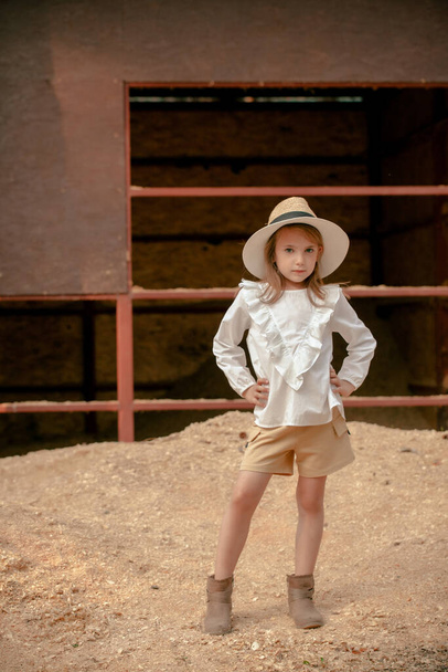 Chica preadolescente de pie akimbo en la pila de serrín cerca del granero vacío de la finca del país - Foto, Imagen