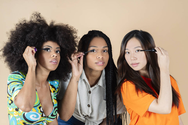 group of women applying mascara on their long eyelashes, multi ethnic, asian, african hispanic, - Foto, imagen