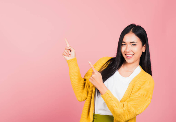 Asiatisches glückliches Porträt schöne süße junge Frau stehend macht Geste zwei Finger nach oben über die Präsentation Produkt etwas, Studioaufnahme isoliert auf rosa Hintergrund mit Kopierraum - Foto, Bild