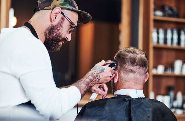 Cada penteado conta uma história. Tiro cortado de um belo barbeiro dando a um cliente um corte de cabelo dentro de sua barbearia. - Foto, Imagem