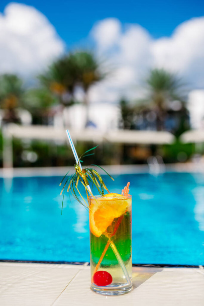 Two Colorful Tropical Cocktails near the Swimming Pool on the Background of Warm Blue Sea. Exotic Summer Vacation. - Foto, Imagen