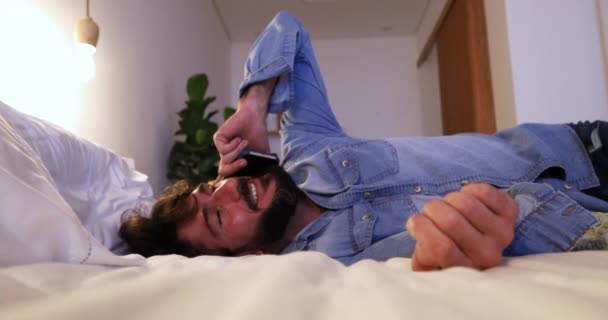 Boční pohled na mladého muže pomocí smartphone v noci ve své posteli. - Záběry, video
