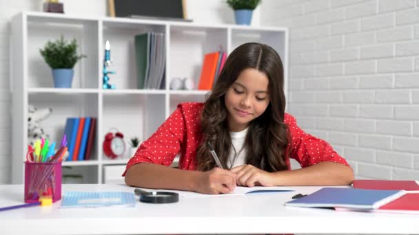 Девочка ребенок писать в блокнот делать домашнее задание на школьном столе, учиться - Кадры, видео
