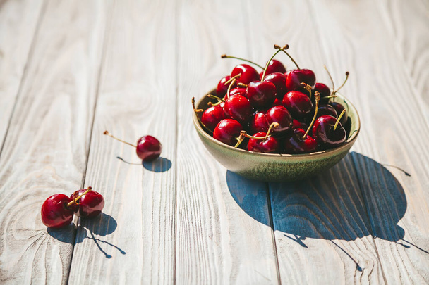 Ripe and tasty cherry in a bowl on a wooden background - Foto, Imagem