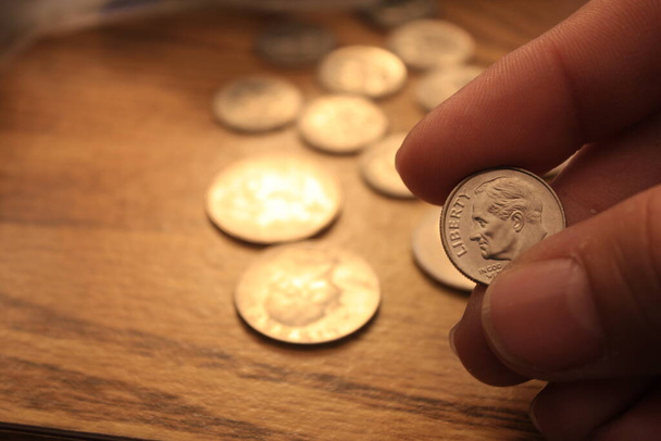 Monety dziesięciocentówkowe są walutą Ameryki. W rękach mężczyzn.. - Zdjęcie, obraz