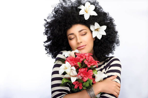 Beautiful young woman hugging a bouquet of flowers over white background with copy space - Fotografie, Obrázek