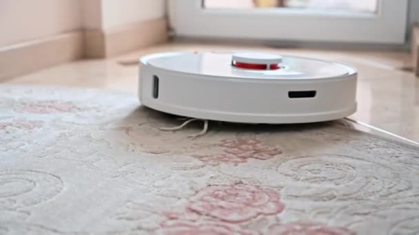 Работает роботизированный пылесос дома, движется по ковру - Кадры, видео