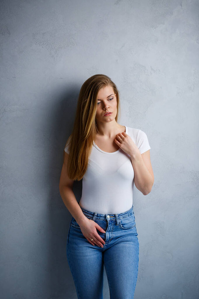 Close-up portrait of a young beautiful woman with blond hair of European appearance. Dressed in a white T-shirt. Emotional photo of a person - Photo, Image