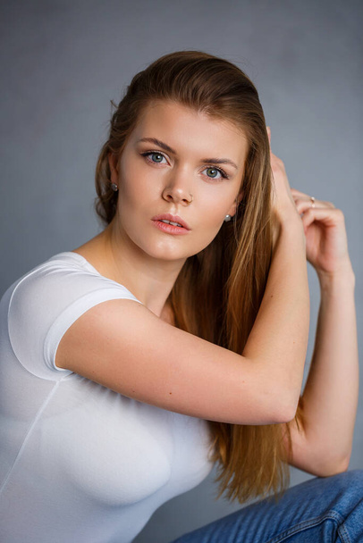 Retrato de una joven hermosa mujer con el pelo rubio de aspecto europeo. Vestido con una camiseta blanca. Foto emocional de una persona - Foto, Imagen