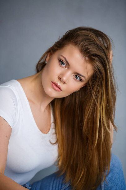 Portrait of a young beautiful woman with blond hair of European appearance. Dressed in a white T-shirt. Emotional photo of a person - Foto, Imagen