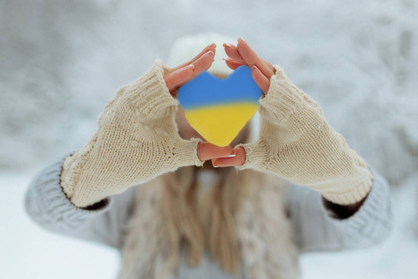 Никакой войны. Февраль начало войны в Украине девушка держит в руках сердце жалкого голубого цвета. Мир на Украине - Фото, изображение