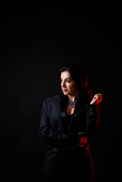 Portrait of a young beautiful woman with dark hair of European appearance. Dressed in a black jacket. Isolated on black background - Fotó, kép