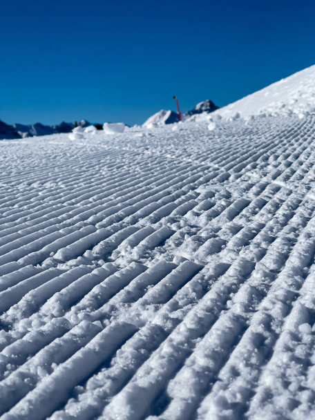 a close up of freshly groomed snow slope and the sky is cloudless and blue - Fotoğraf, Görsel