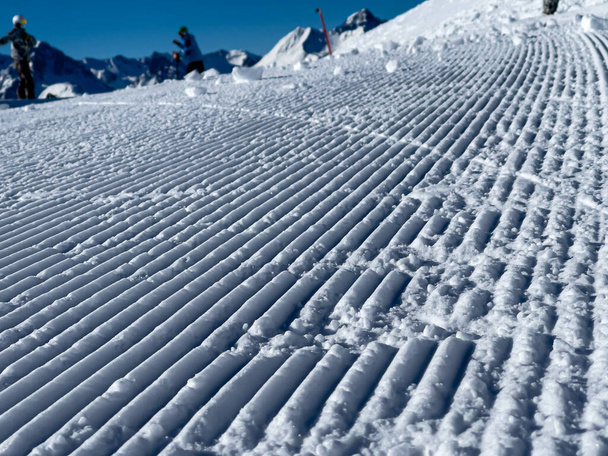 a close up of freshly groomed snow slope and the sky is cloudless and blue - Фото, изображение